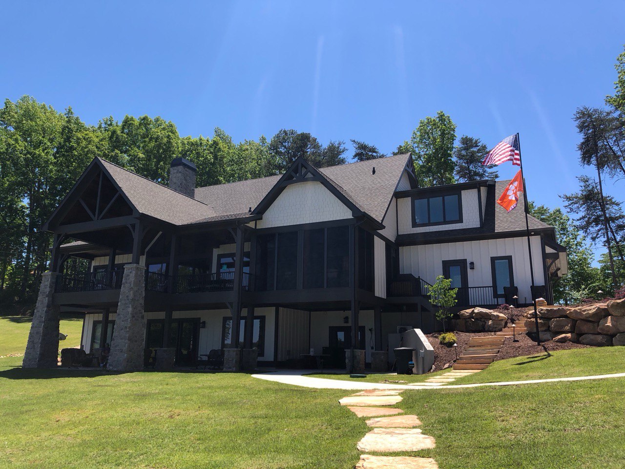 A Phoenix flagpole flying the American flag beside a modern two-story home