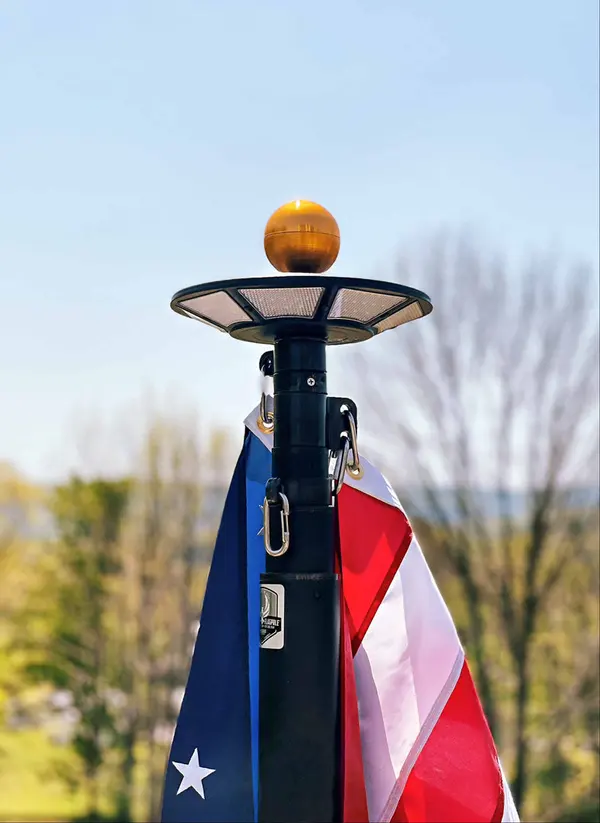 A solar flagpole light installed under the gold ball topper