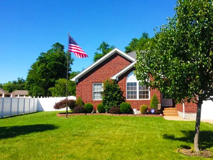 A 20 ft Black Bronze Phoenix at a brick home with a white fence