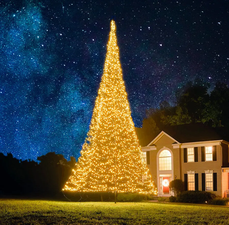 A Patriot Glo LED flagpole Christmas tree lit at night in front of a two-story home